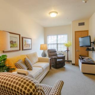 A cozy living room with a sofa, armchair, and mounted TV.