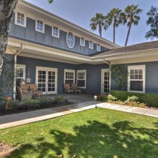 A two-story residential house with a well-kept lawn and surrounding palm trees.