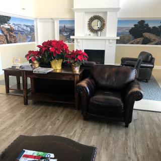 A cozy living room setup featuring a leather armchair, a wooden coffee table adorned with vibrant flowers, and inviting wall decor.