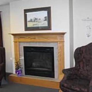 A cozy living room featuring a wooden fireplace with a framed artwork above it.