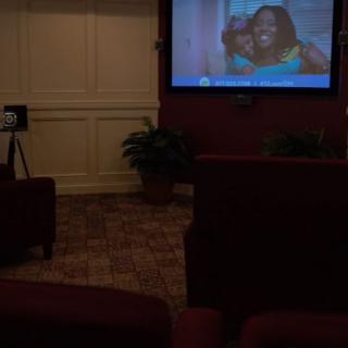 A cozy home theater setup with seating and a projector screen displaying a show.