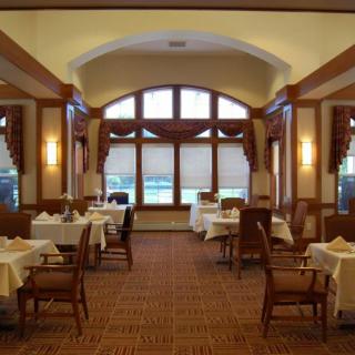 An elegant restaurant dining room with neatly set tables and warm lighting.