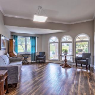 A spacious living room with hardwood floors, modern furniture, and large windows allowing natural light to fill the space.