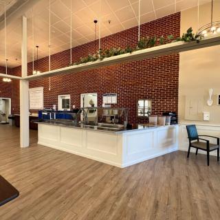 A modern cafe interior featuring a stylish counter, brick walls, and wood flooring.