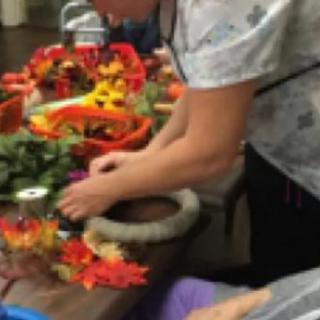 A person creating an autumn-themed wreath with colorful foliage and decorations.