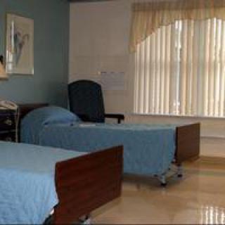 A hospital room with two beds and a window with blinds.