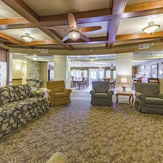 A spacious living room with comfortable seating, warm lighting, and a ceiling fan.