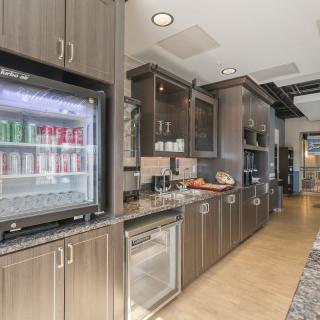 A modern kitchen interior featuring sleek cabinets and a glass-front refrigerator.