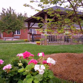 A scenic view of a house with a beautiful garden, showcasing vibrant flowers in the foreground.