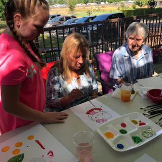 A joyful outdoor painting session where children and adults come together to create art.