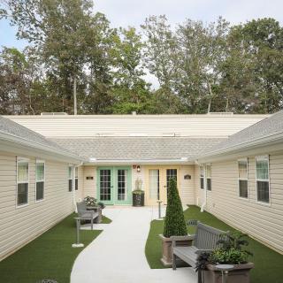A peaceful courtyard with benches, greenery, and an inviting pathway surrounded by buildings.
