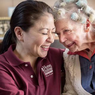 A caregiver shares a joyful moment with a senior woman in a nursing home.