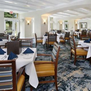 A spacious and elegantly designed restaurant dining area with neatly arranged tables and chairs, set with tableware.