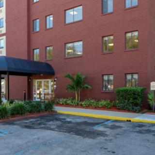 The entrance to a brick building with a canopy and well-maintained landscaping.
