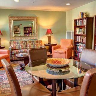 A cozy and well-decorated living room featuring comfortable seating, bookshelves, and warm lighting.