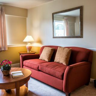 Cozy living room with a sofa, cushions, and a warm lamp.