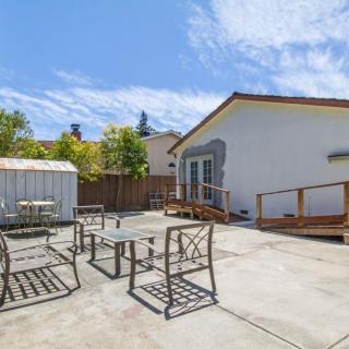 A spacious backyard with outdoor seating, a shed, and a sunny atmosphere.