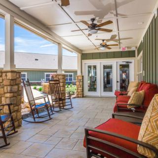 A cozy outdoor patio with rocking chairs and ceiling fans, offering a relaxing seating area.