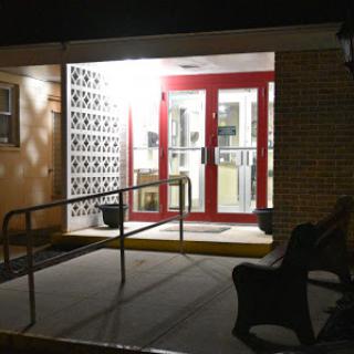 A brightly lit entrance featuring red doors, visible at night.