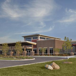 A modern educational building surrounded by a landscaped area under a partly cloudy sky.
