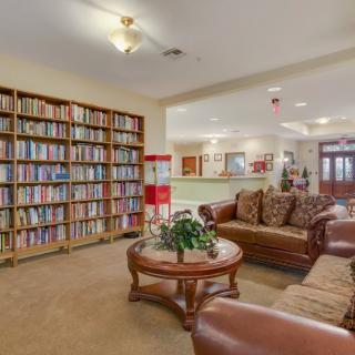 A cozy library and seating area featuring bookshelves, comfortable sofas, and a central table.