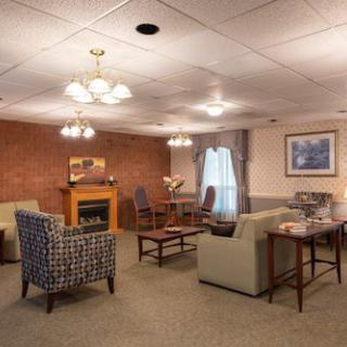 A cozy living room with multiple seating arrangements, featuring a fireplace and elegant chandelier lighting.