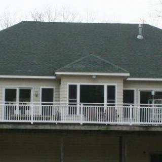 A view of a house with a green roof and a white balcony.