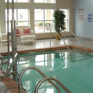 An indoor swimming pool with lounge seating and natural lighting.
