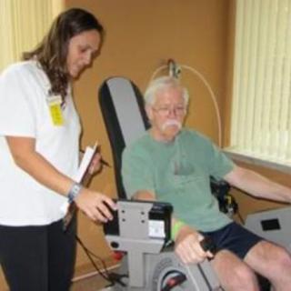A therapist assisting a patient using an exercise machine during a physical therapy session.