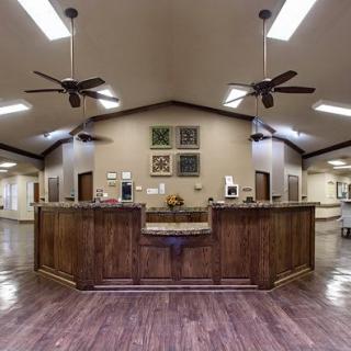 A spacious reception area with a wooden front desk and ceiling fans.