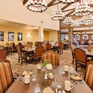 A cozy dining area with elegant chandeliers and neatly arranged tables and chairs.