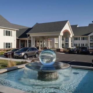 A modern hotel entrance with a prominent fountain feature and parked cars.