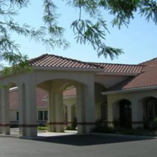 A building with a tiled roof and columned entrance surrounded by trees.