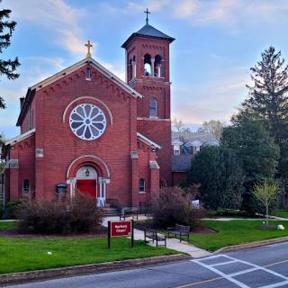 A beautiful brick church with a bell tower set against a serene landscape.