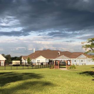 A suburban house with a large green lawn under a cloudy sky.