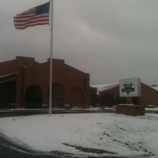 A snowy day at a school with an American flag flying outside.