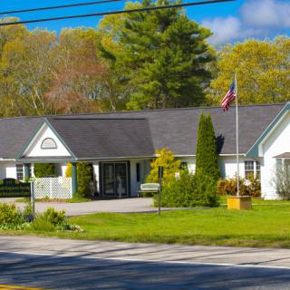 A quaint building surrounded by trees with a flagpole in front, set against a clear blue sky.