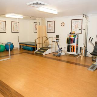 A well-equipped gym or therapy room featuring various exercise machines and tools.