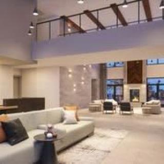 A spacious and modern living room with contemporary furnishings and a high ceiling.