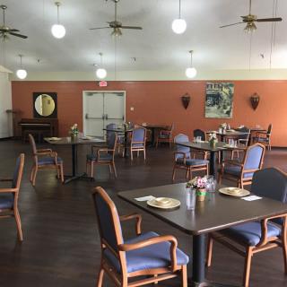 An empty dining room with neatly arranged tables and chairs, featuring warm lighting and a cozy atmosphere.