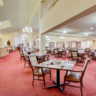 Spacious restaurant dining area with elegant chandeliers and neatly arranged tables.