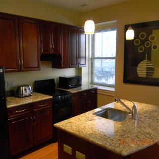 A modern kitchen with dark wooden cabinets and a granite countertop island.
