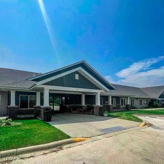 A modern residential building with a well-maintained lawn and driveway under a bright blue sky.