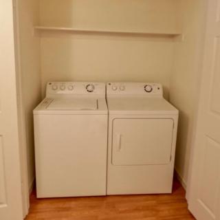 A compact laundry room setup with a washer and dryer beneath a shelf.