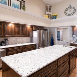 A modern kitchen with a large granite countertop and wooden cabinets.