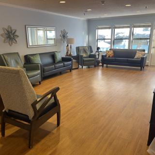 A spacious living room with multiple sofas and chairs arranged on a laminate floor.
