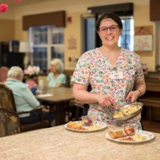 A dedicated healthcare worker serves meals in an assisted living facility, ensuring the residents receive nutritious food.
