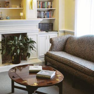 A cozy living room with a sofa, coffee table, bookshelf, and indoor plants.
