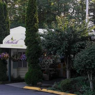 Entrance to a restaurant with an awning surrounded by lush greenery and flowers.