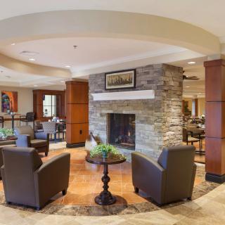 A modern lobby with a cozy seating area featuring a stone fireplace and comfortable chairs.